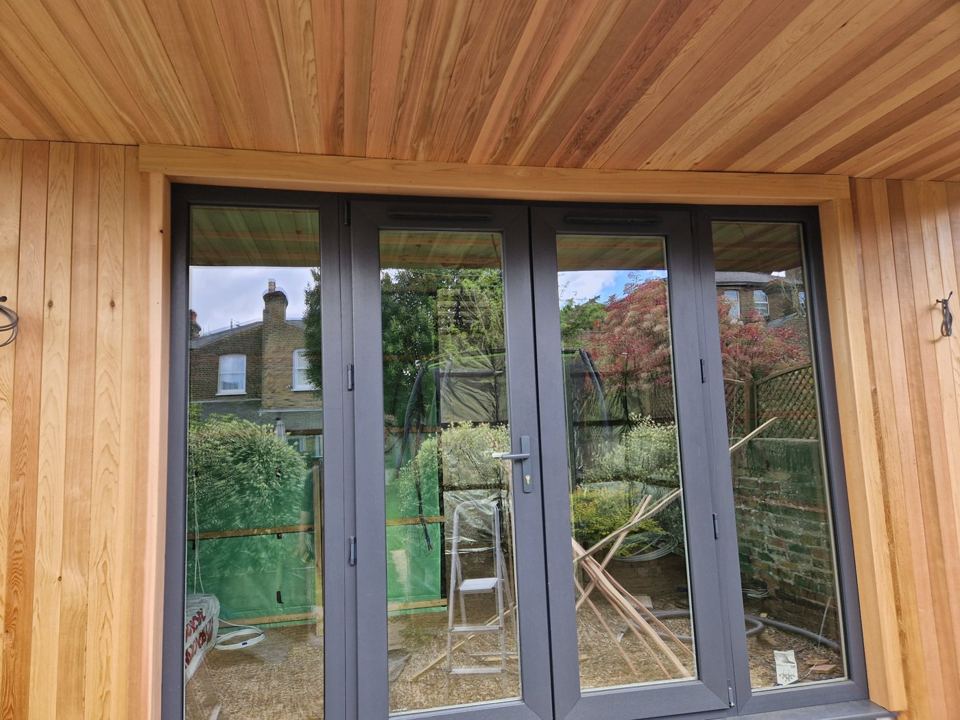 Anthracite bifold doors under a cedar soffit